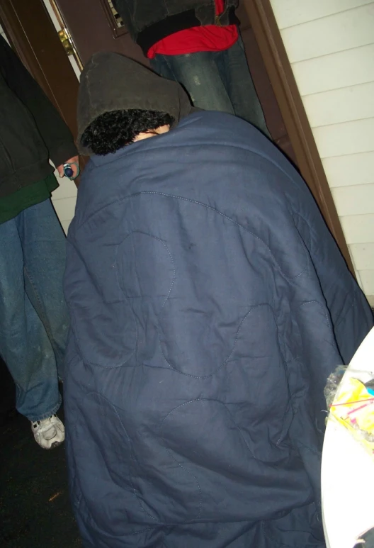 a person wrapped up with a blanket outside a house