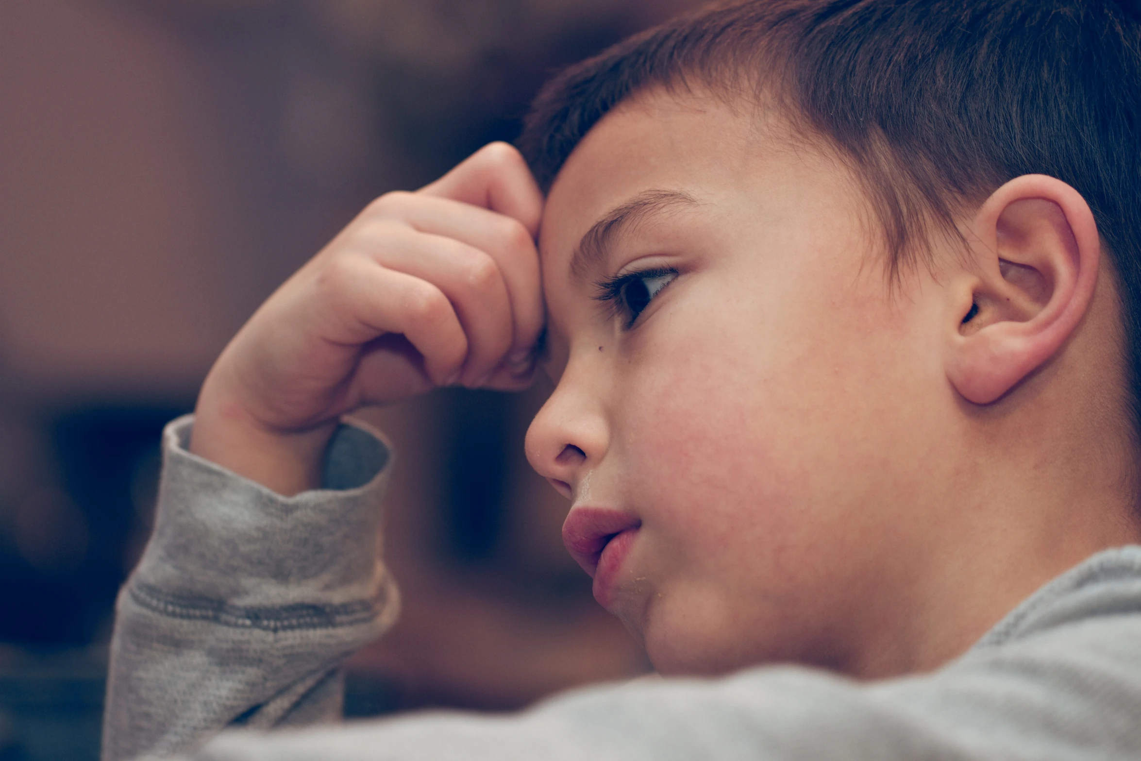 a young child in gray sweater looking at soing