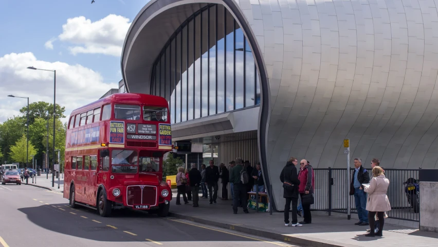 a red bus parked next to a curb filled with people