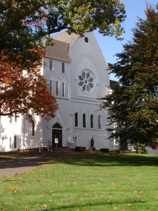 a tall white church sits next to a tree