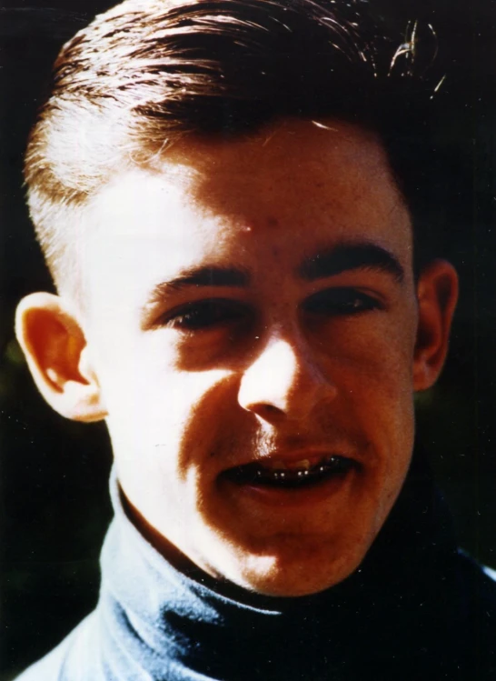 a young man with a pony tail and a dark polo shirt