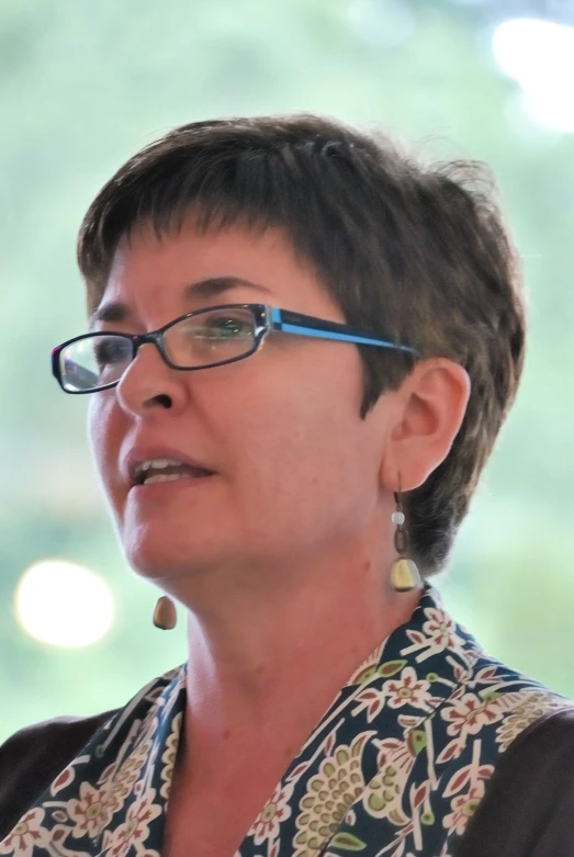 a woman with glasses stands in front of a window