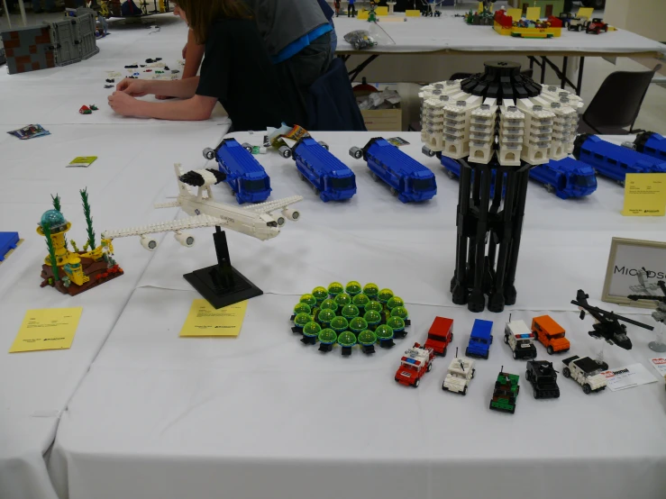 a group of people in front of a table with lego structures