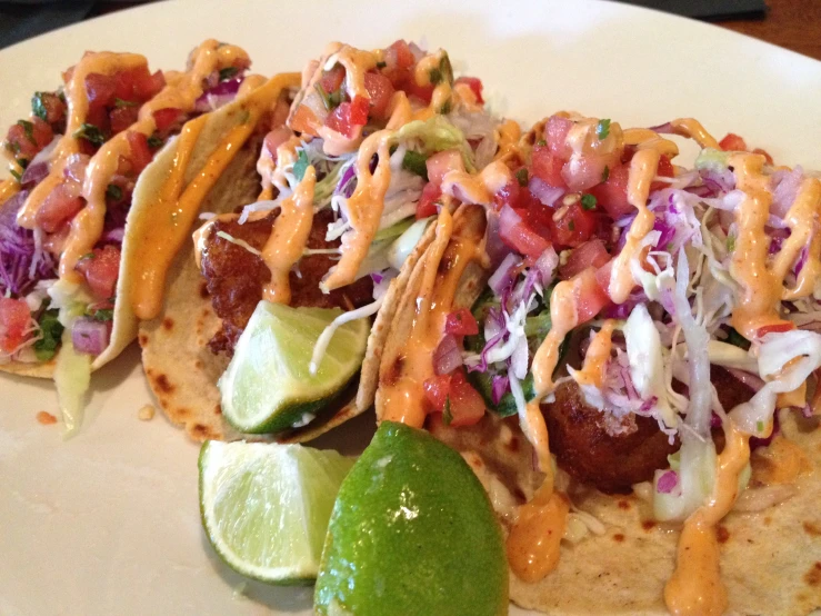 a plate topped with tacos next to a lime and a lime wedge