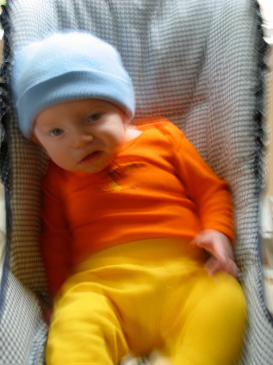 a baby in a blue hat and orange outfit