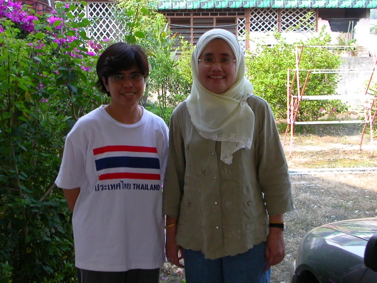 two people that are standing in front of some bushes