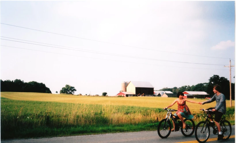 two people on bicycles stopped on the side of a road