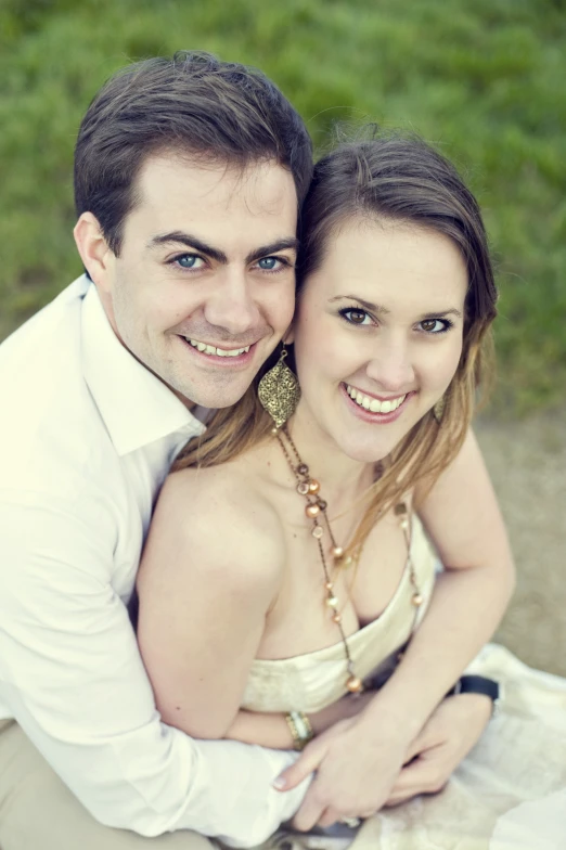 a smiling young couple with necklaces on sitting outside