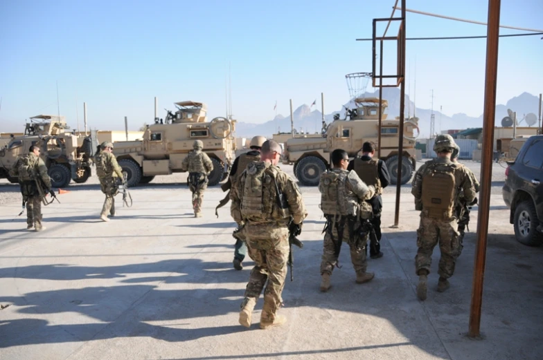 a group of military men standing next to military vehicles