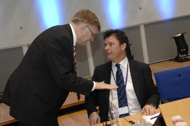 two men are sitting at a table discussing soing