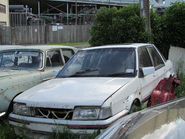 several rusted cars are shown parked in a yard