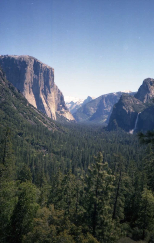 trees and mountains surrounding a valley in a mountain range