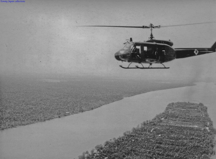 a helicopter flies low to the ground above water