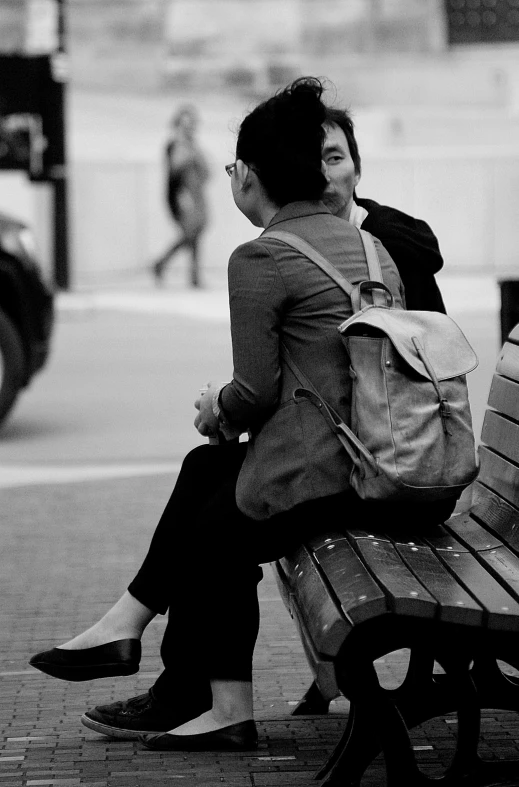 two people sitting on a bench in a city