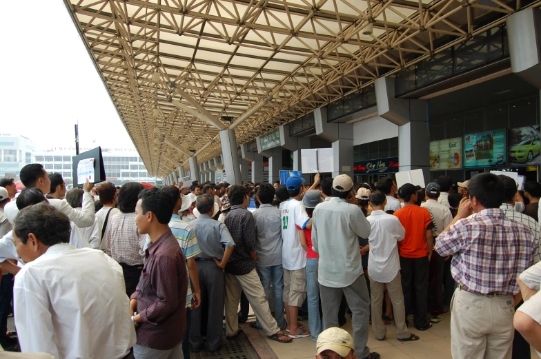 a large group of people stand near a subway station