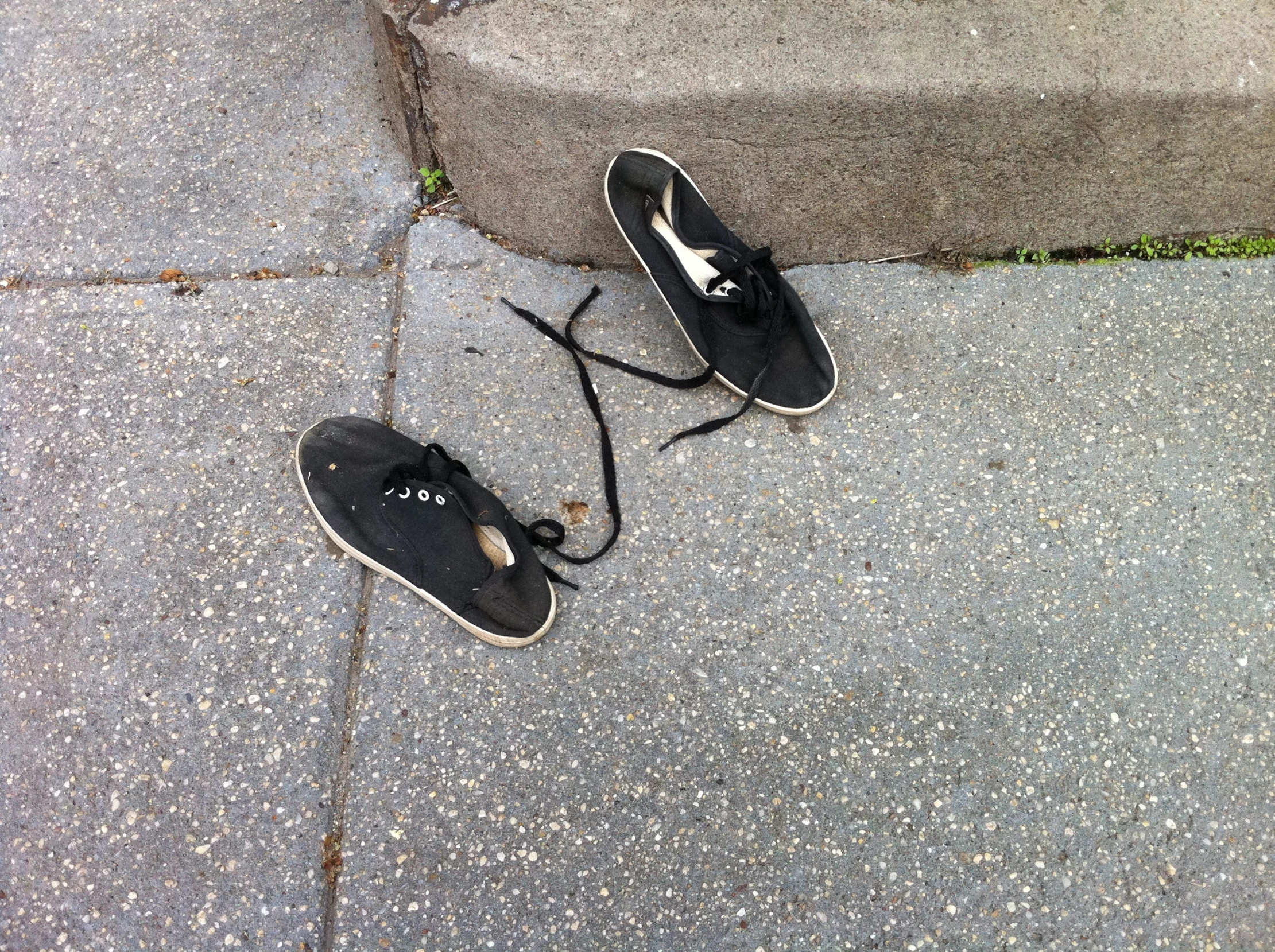 a pair of shoes sitting on the sidewalk near a stair rail