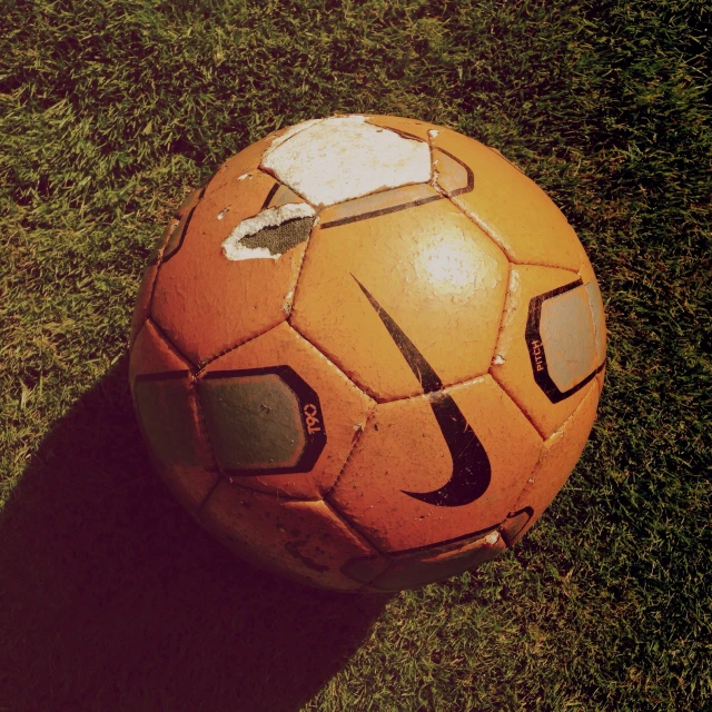a orange soccer ball on green grass with the letter j in black