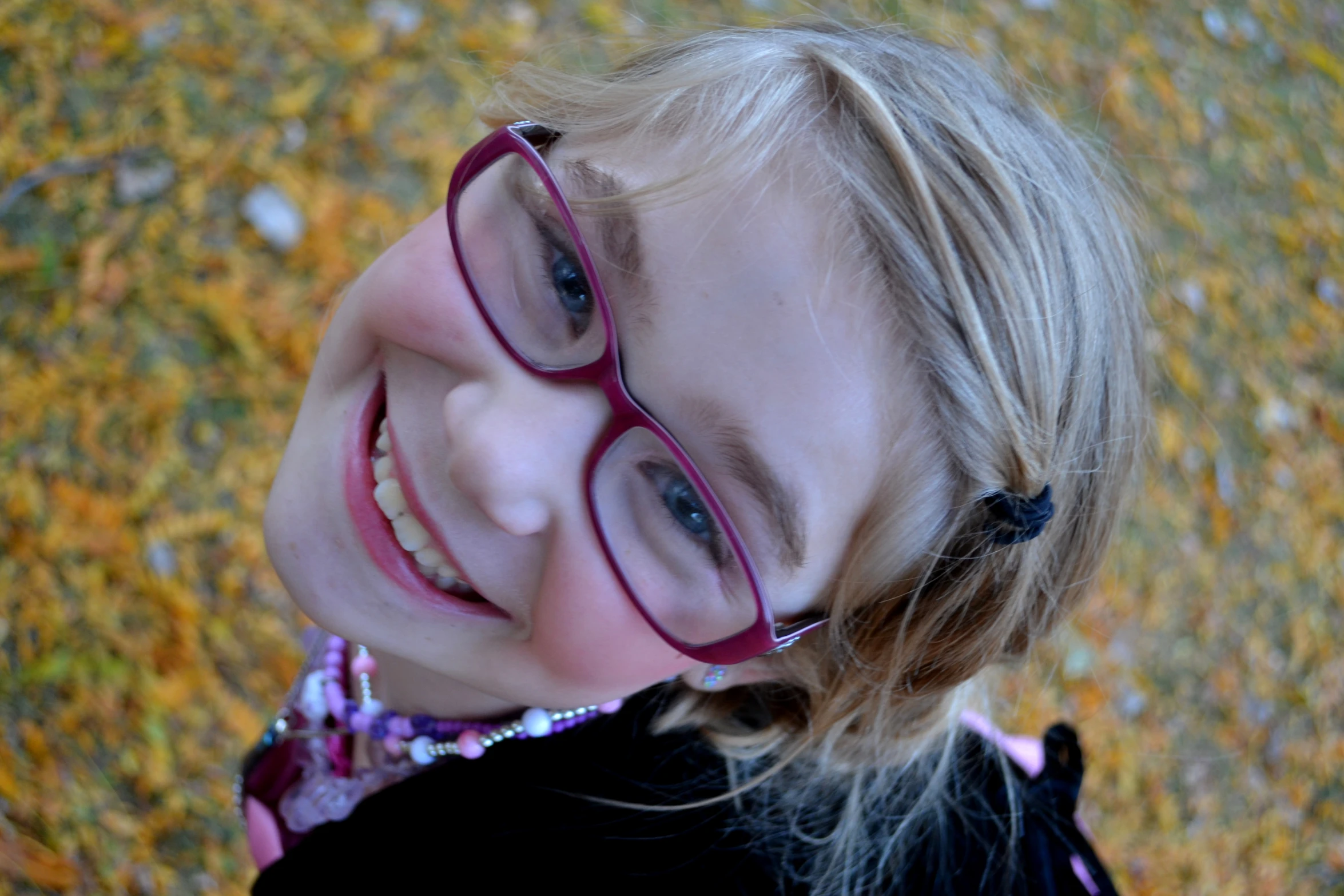 a little girl is wearing red glasses and has blond hair