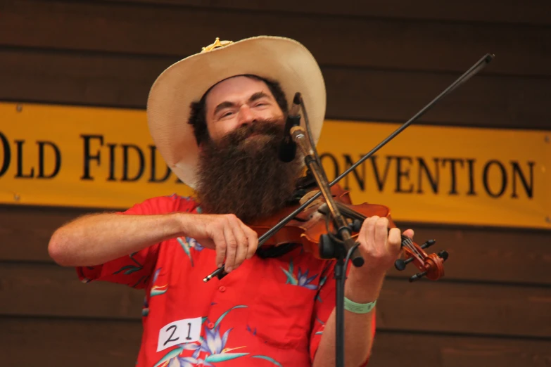 a man with a cowboy hat plays violin