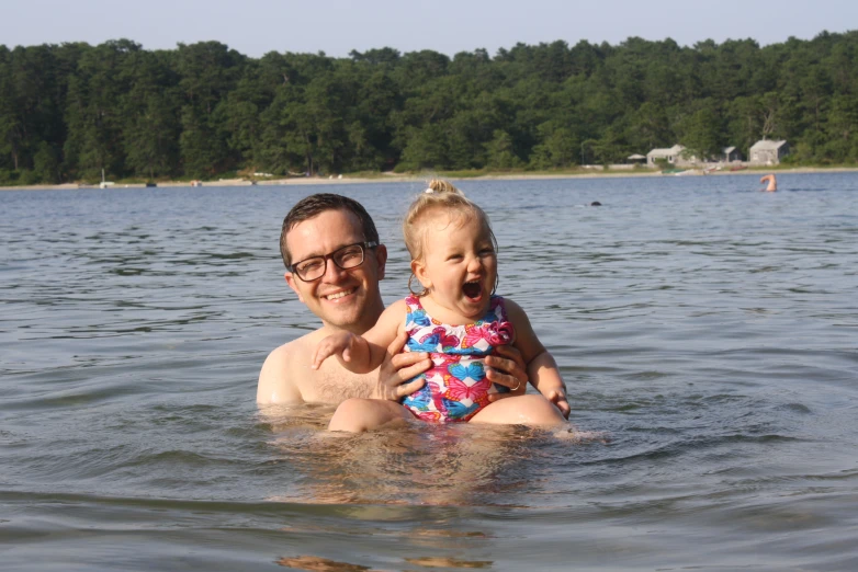 the man is holding the girl in the water