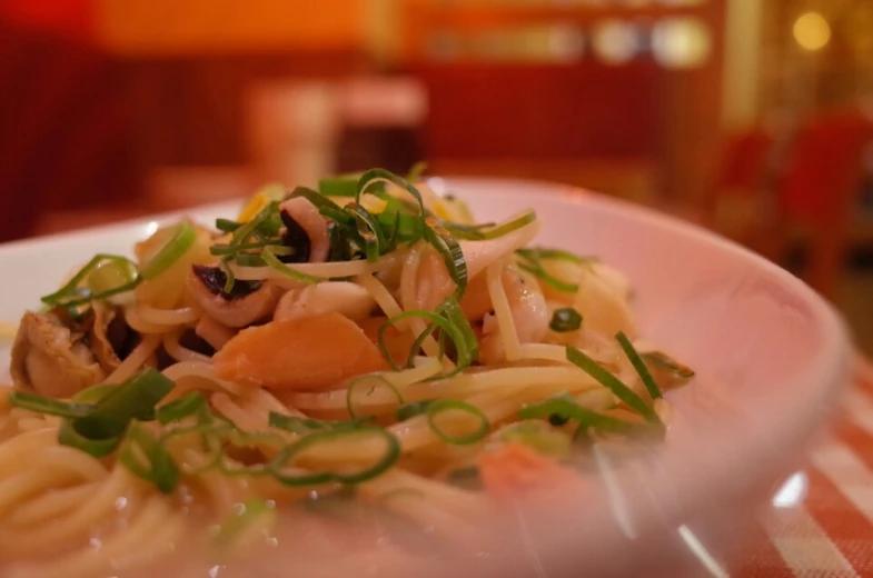 noodles, vegetables and onions are in a white plate