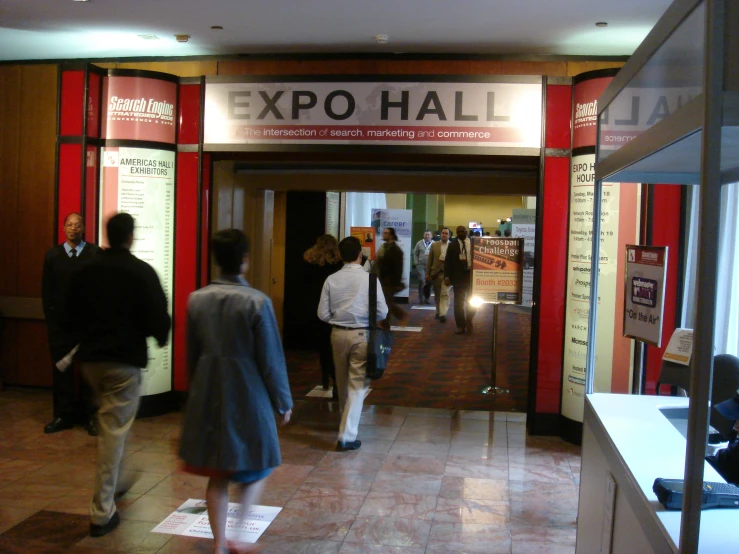 people walk around a museum that has posters and exhibit displays