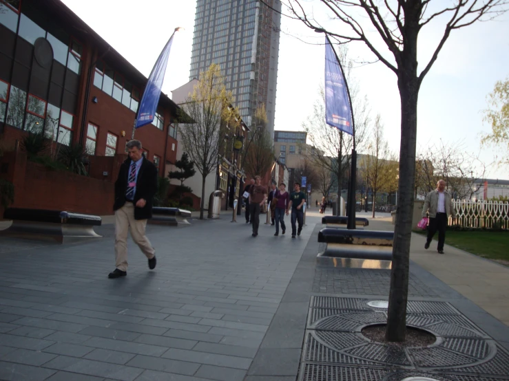 people walk down a sidewalk near a brick building