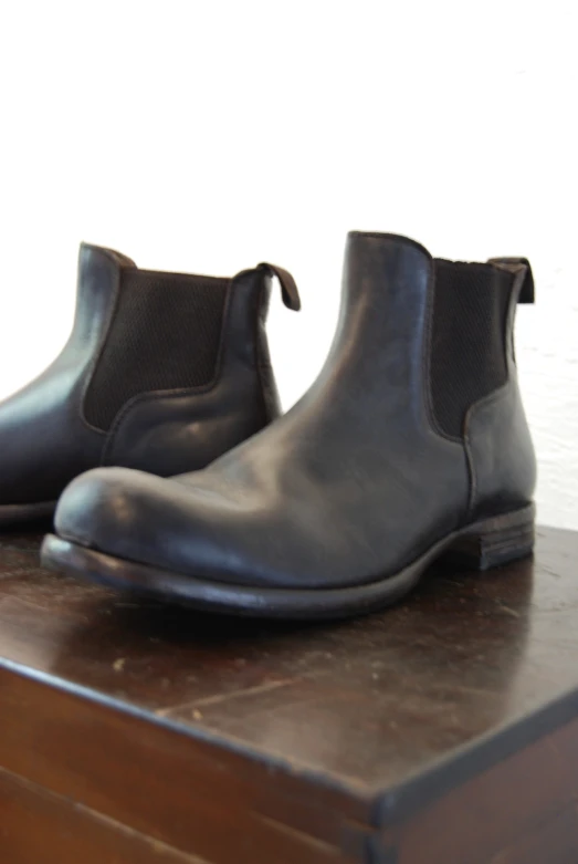 two black shoes sitting on top of a wooden table