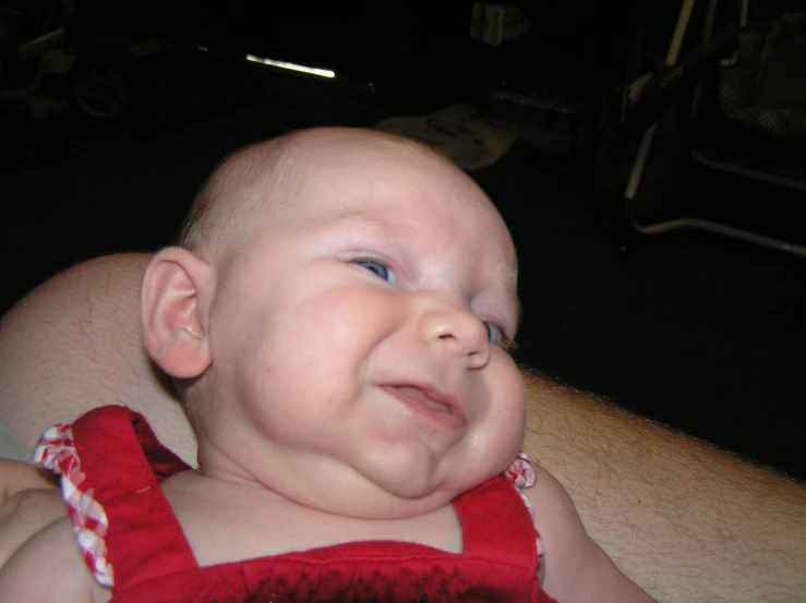 a baby wearing a red suspender smiling