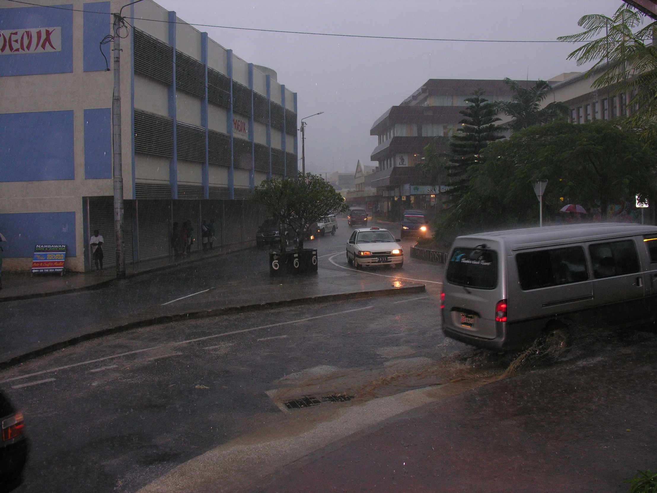 a couple of vehicles are driving down a rainy city street