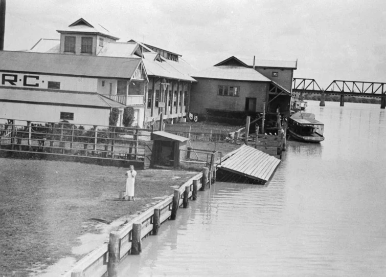 an old po shows a river that runs past a dock with people standing around