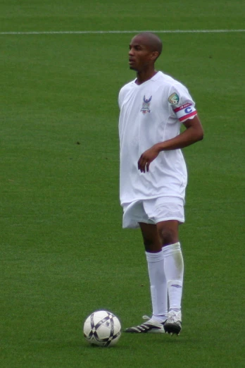 a young man in white is playing soccer on green grass