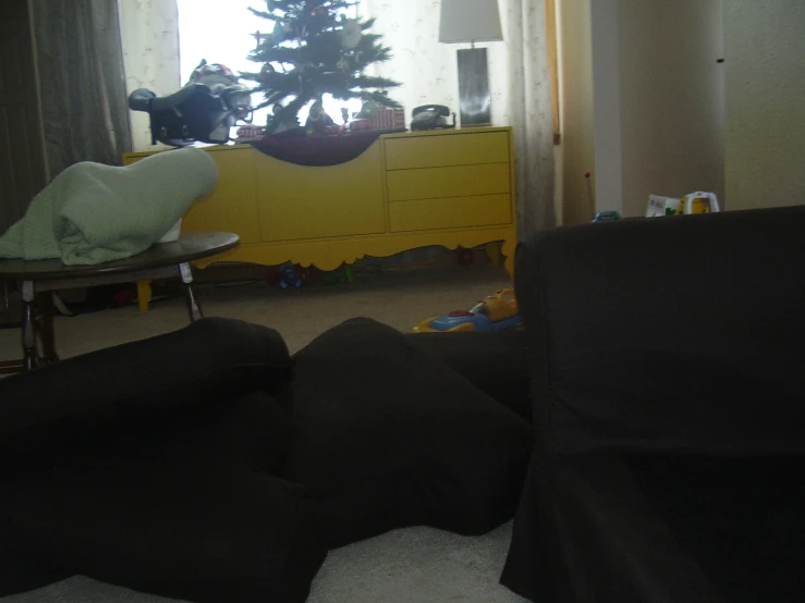 a living room with a yellow dresser and black chair