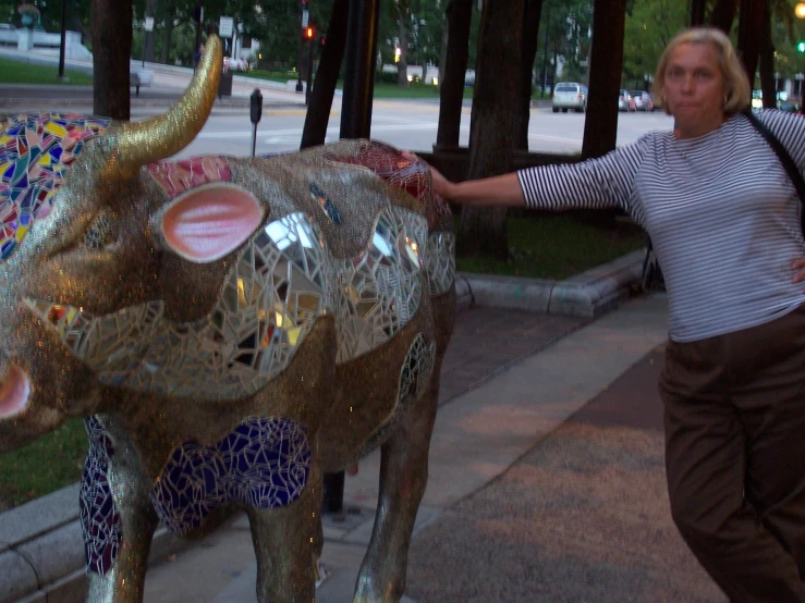 a woman standing next to a glass sculpture of an elephant