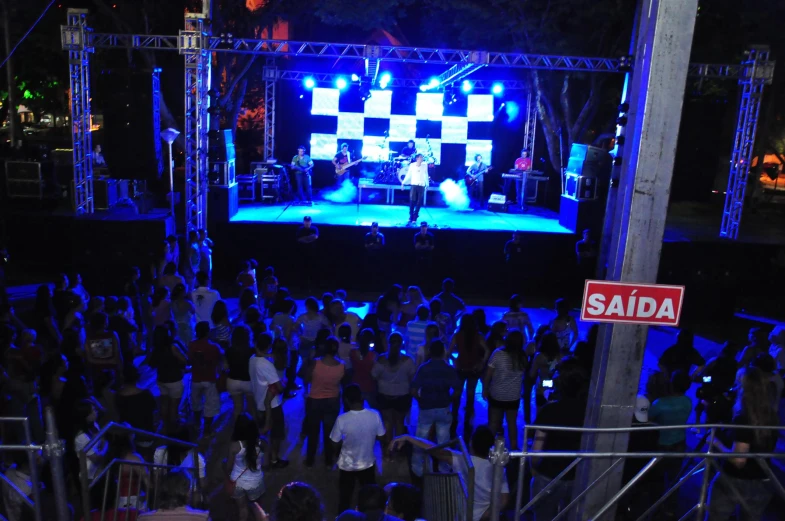 large crowd watching a stage with a checkered screen