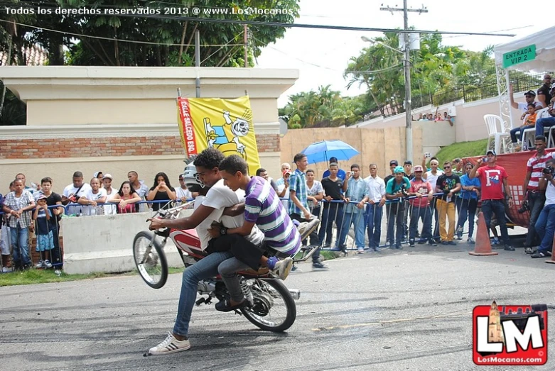 two men racing motorcycles down a street with spectators