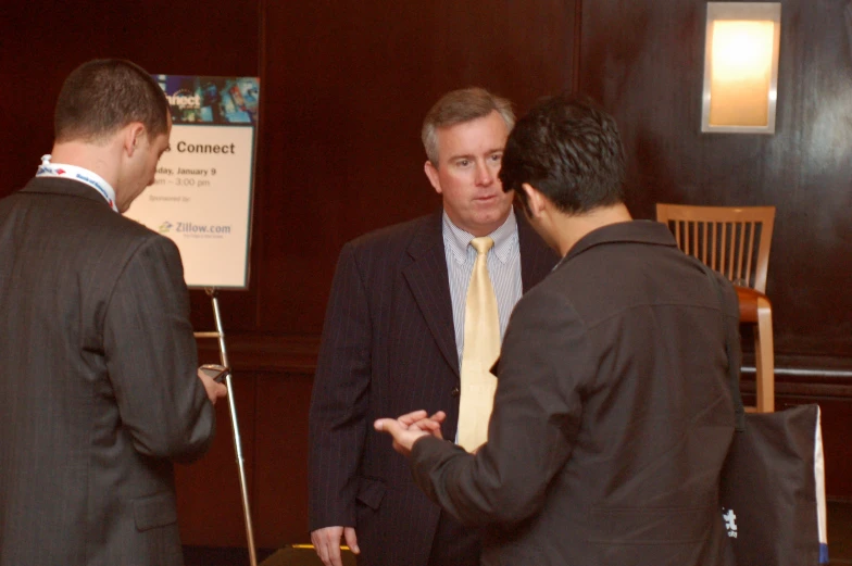 three men in suits talking to each other