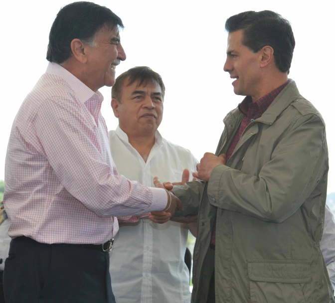 two men shake hands next to each other in a crowd