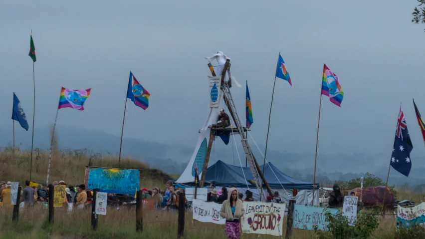 people gathered around tents in the field with flags and banners flying from them