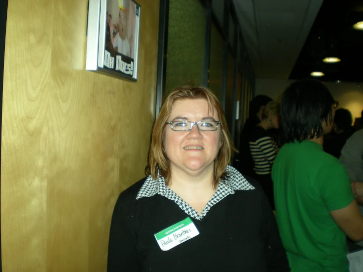 a woman with a name tag standing by a wall