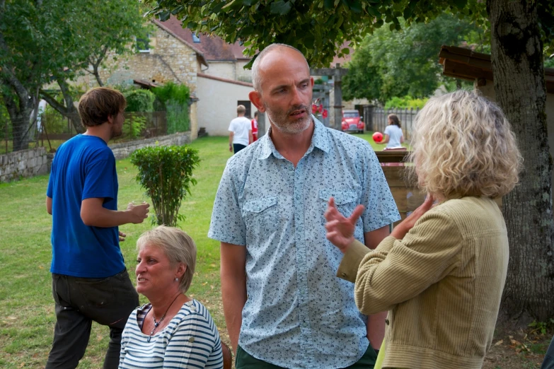 three older people standing around talking on the grass