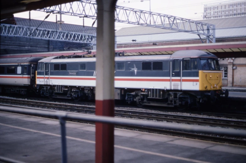 a white and grey train with yellow front passing through a station