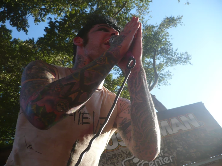 a man with tattoos on his arms sings into a microphone