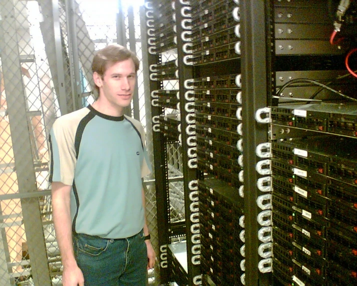 a man standing in front of a rack of computer monitors