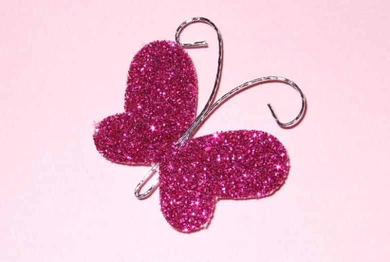 a pink glittery erfly with a metal hook