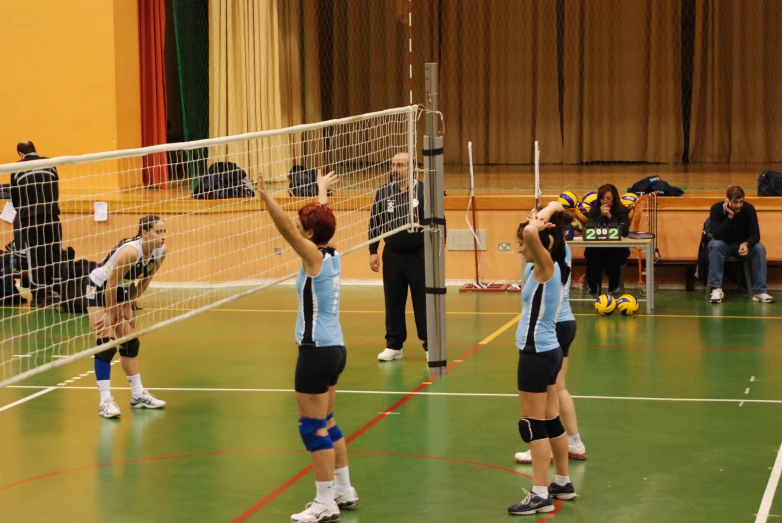 three women are holding volleyball racquets in front of the net