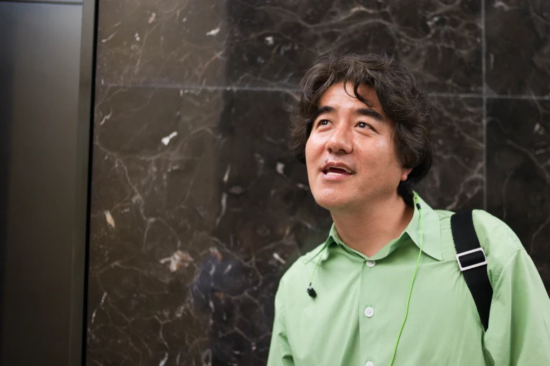 man standing near a marble wall looking to the side