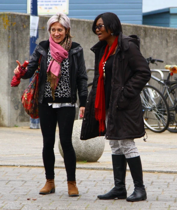 two woman standing next to each other on a brick road