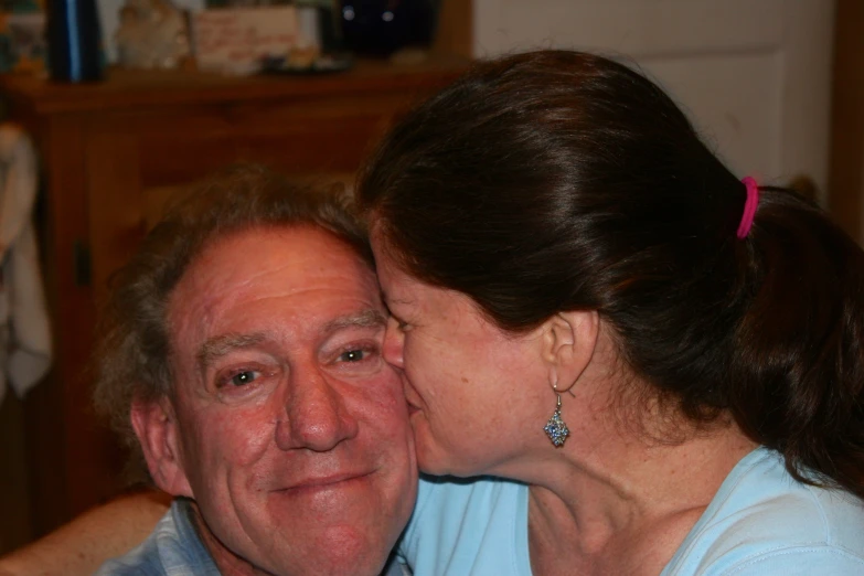 an elderly man kissing a woman's forehead