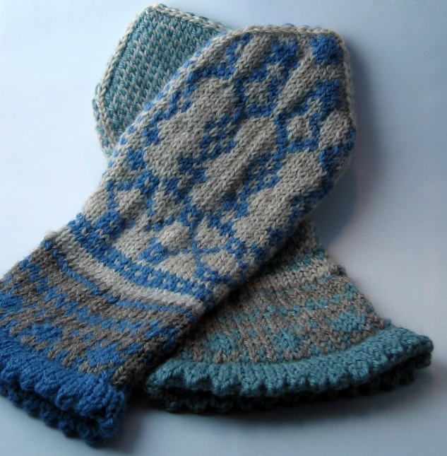 the blue and gray knitted mittens have been placed together